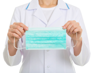 A person in a white lab coat holds a surgical face mask by its ear loops with both hands, presenting it directly forward.