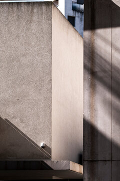 Raw concrete corner with deep shadows and subtle textures, expressing architectural minimalism and vertical tension suitable for use as a clean visual background