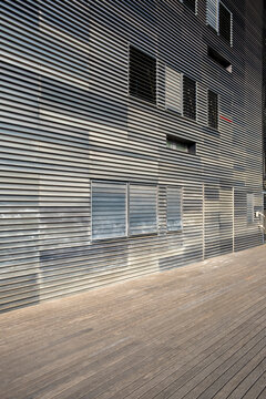 Linear metallic architecture with repetitive horizontal patterns and reflections, captured in sharp daylight for modern commercial use as structural background or texture