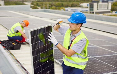Technician or worker installing and maintaining solar panels on the roof. The photovoltaic system...