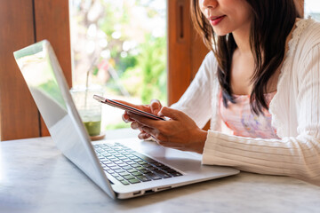 Young Asian woman with drinks using phone and working with laptop in cafe, Modern lifestyle