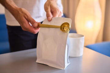 Pouring freshly ground coffee beans into a measuring cup for a perfect morning brew