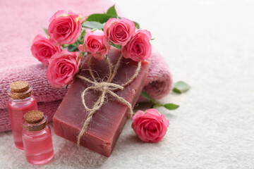 Soap bar, towels, essential oils and beautiful roses on beige table, closeup. Space for text