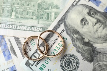 Two gold wedding rings on dollar banknotes, top view