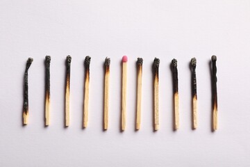 Burnt and whole matches on light grey background, flat lay