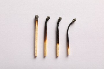 Burnt matches on light grey background, flat lay