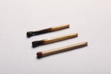 Burnt and whole matches on grey background, closeup