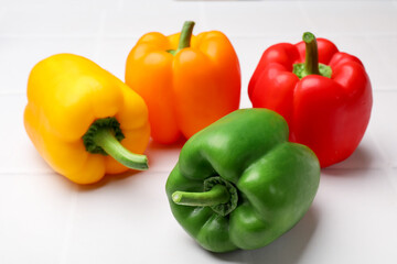 Fresh colorful bell peppers on white table, closeup
