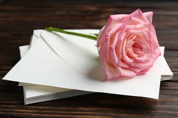 Stack of love letters and beautiful rose on wooden table, closeup