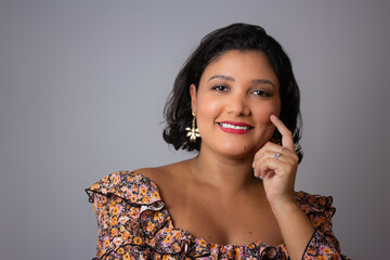 Beautiful short hair woman smiling with hand on her face. Perfect for friendly and happy concepts, femininity and beauty. Horizontal studio portrait with copy space on gray background.