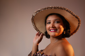 Beautiful friendly woman wearing a straw hat, smiling at camera. Perfect for vacations, beauty, summer,  sunset light and happiness themes. Horizontal studio portrait with copy space.