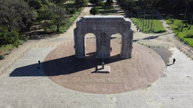Drone footage of Parque da Reden&ccedil;&atilde;o in Porto Alegre, Brazil, showing the iconic arch and a panoramic view of the city skyline in the background.