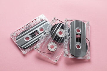 Audio cassettes with magnetic tapes on pink background, above view