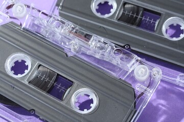 Audio cassettes with magnetic tapes on violet background, macro view