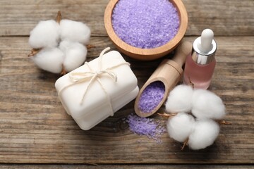 Obraz na płótnie Canvas Soap bars, cosmetic products and cotton flowers on wooden table, above view