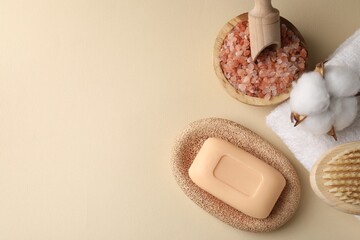 Flat lay composition with soap bar, sea salt and cotton flower on beige background. Space for text