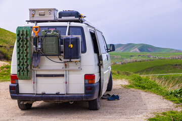 White van parked on roadside with adventure gear in rural area