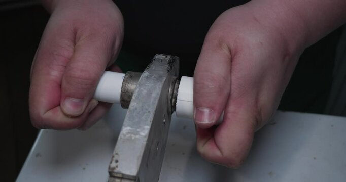 A close -up plumbing connecting polypropylene pipes using a special tool, providing a connection without a leak for a reliable water supply system. A man warms and inserts polypropylene pipes.