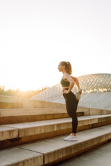 A sporty woman doing exercises outdoors at sunset. Beautiful woman in sportswear enjoying a workout...