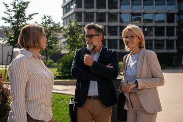 Diverse business people having pleasant outdoor discussion about future plans and projects in urban...