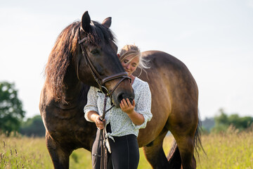 Young woman lovingly caresses her brown horse while standing in sunlit meadow. Heartfelt moment...