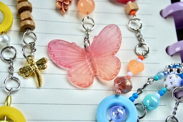 Colorful orange red butterfly beads isolated on horizontal note book lined paper and bag charm accessories background.