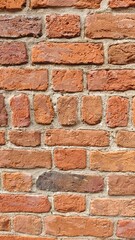 Naklejka premium Close-up view of a textured red brick wall with visible mortar lines. The image symbolizes strength, construction, and classic architectural elements