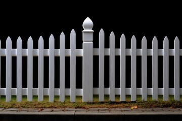 White picket fence with a decorative post on a black background and grass below