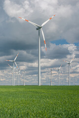 Cover page with beautiful green farm landscape with light and shadow waves in Germany with clouds in sky, and wind turbines to generate electrical power.