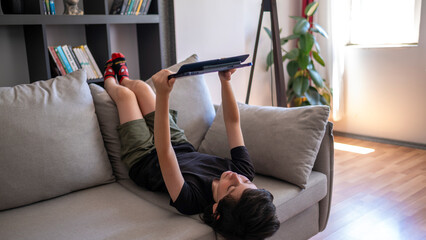 Child lying on couch using tablet