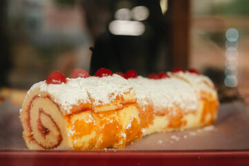 Cherry-topped jelly roll cake dusted with powdered sugar
