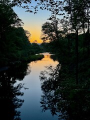 Obraz premium Summer vibes. Night at sunset. blue orange sky which reflects in the waters of Windham Path in Catskill Mountains ski town. Mountain peaks in the distance. Clear sky at dusk. Quiet and serene beauty