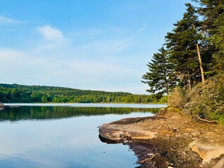 Breathtaking mountain peak at sunset. Stunning scenic view. North South Lake Campground in the Catskill Mountains. Serene summer, dusk. Clear calm blue orange purple sky clouds reflect over lake. © theplantedwanderer