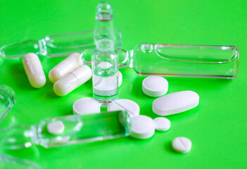 Pharmaceutical preparations and ampoules, arranged on a vibrant green background, symbolize medical...