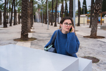 University student making an important phone call while studying outdoors in a park