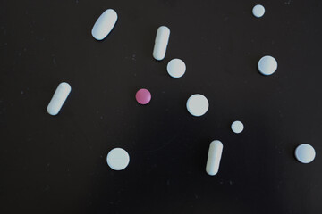 A scattering of colorful pills and capsules on a black background creates a visual emphasis on the theme of health. This composition symbolizes pharmaceutical products, treatment, and the importance o