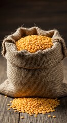 A burlap sack filled with yellow lentils sits on a rustic wooden table