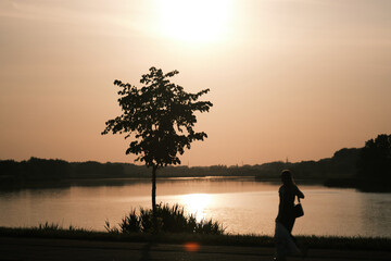 Silhouette of a girl walking by the lake at sunset
