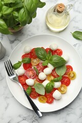 Tasty salad with mozzarella, tomatoes and basil served on white marble table, flat lay