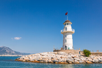 A white lighthouse on the stone pier of Alanya Turkey