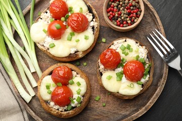 Tasty stuffed mushrooms served on black table, flat lay