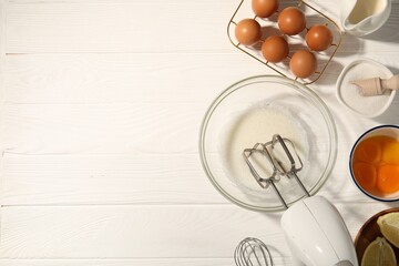 Hand mixer, egg whites in bowl, eggs and other products on white wooden table, flat lay. Space for text