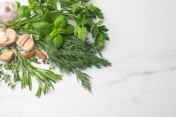 Different fresh herbs and spices on white marble table, flat lay. Space for text