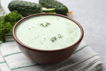Tasty cucumber soup and ingredients on light grey table, closeup