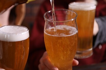 Pouring beer into woman's glass indoors, closeup