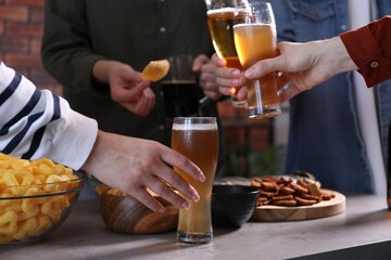 Friends with beer and snacks at grey table, closeup
