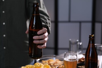 Woman with bottle of beer indoors, closeup