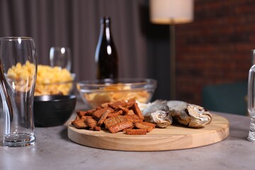 Beer, glasses and snacks on grey table indoors, closeup