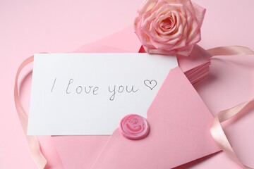 Stack of letters, card with phrase I Love You and rose flower on pink background, closeup