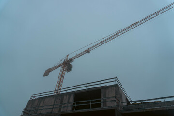 Fototapeta premium Construction crane above building in foggy weather